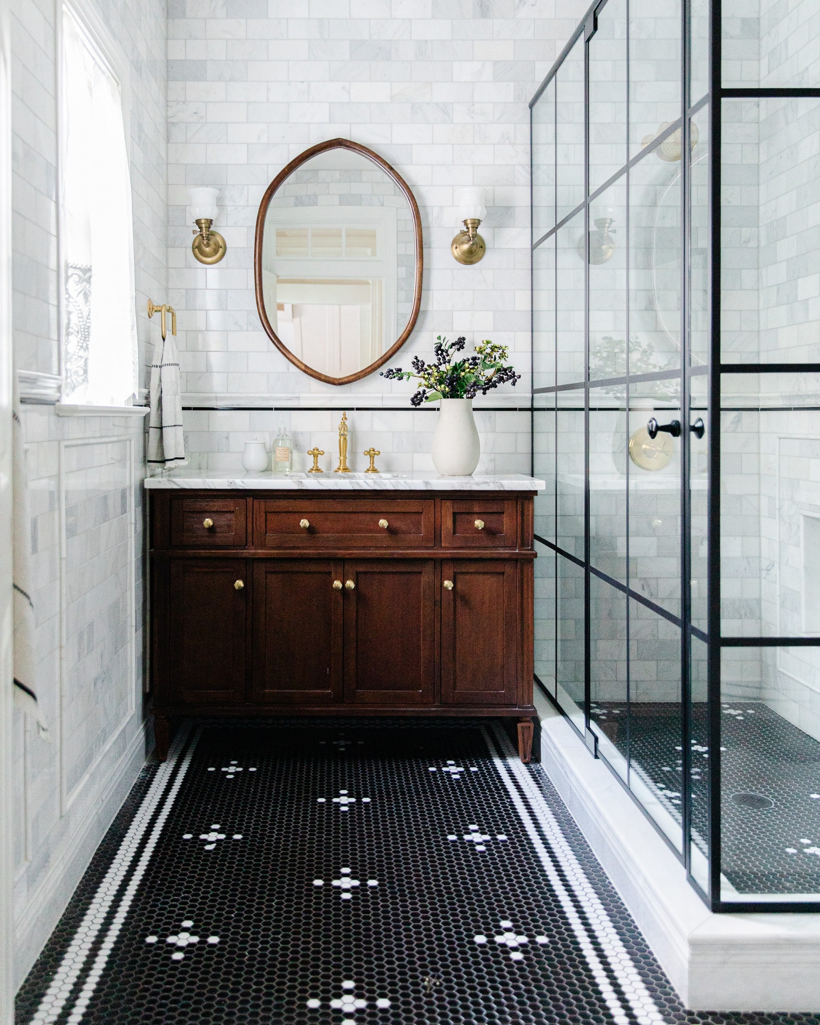 Renovated black bathroom with brass fixtures and marble tile clad
