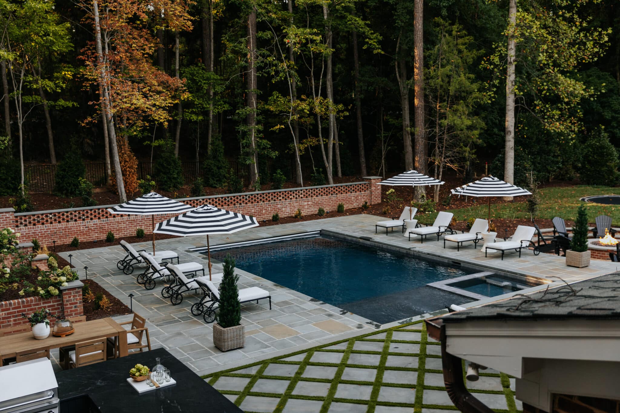 Chris Loves Julia | Back patio and in-ground pool surrounded by black iron furniture with white cushions
