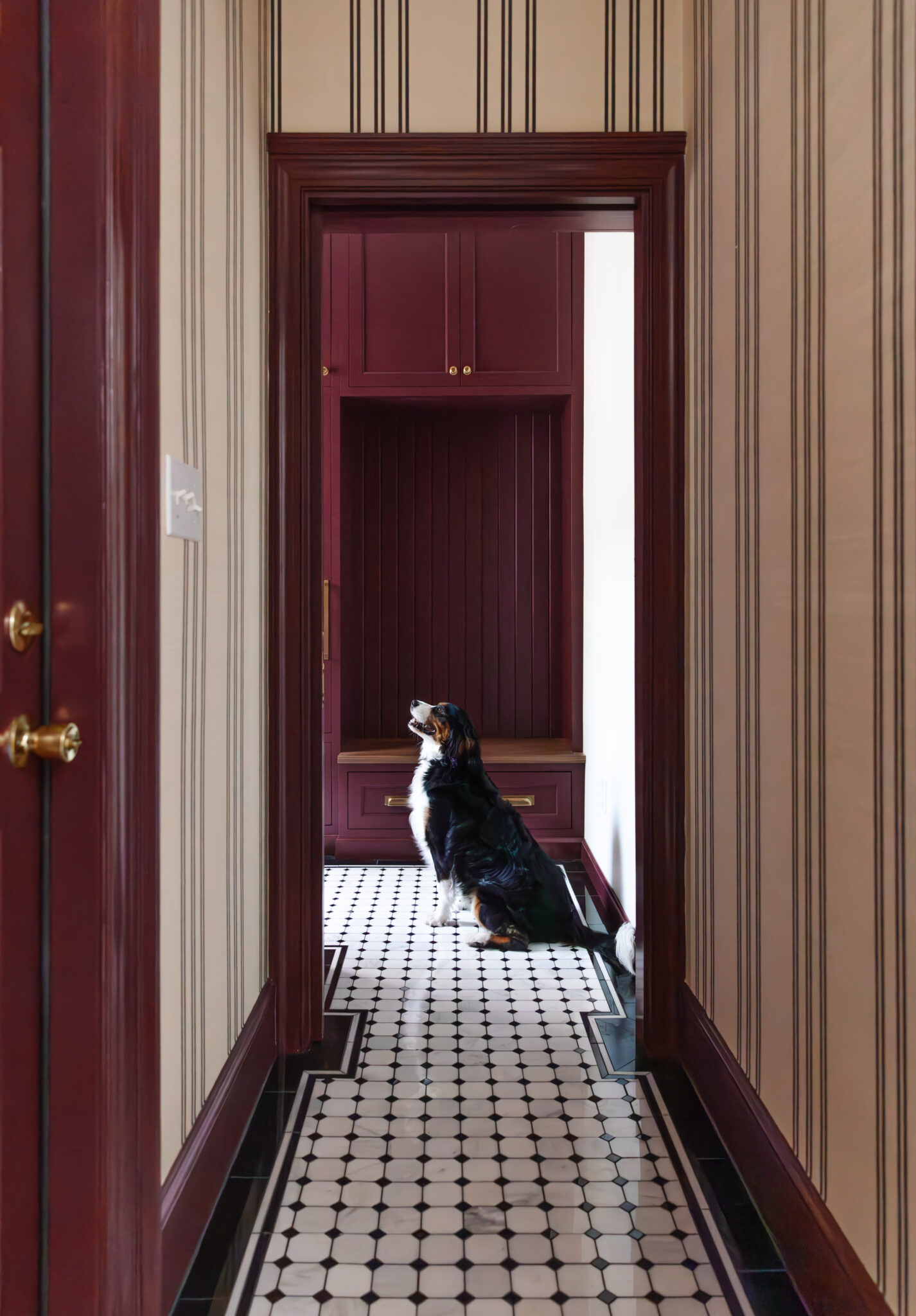 Chris Loves Julia | Mudroom hallway with grasscloth wallpaper, tiled floor and red trim