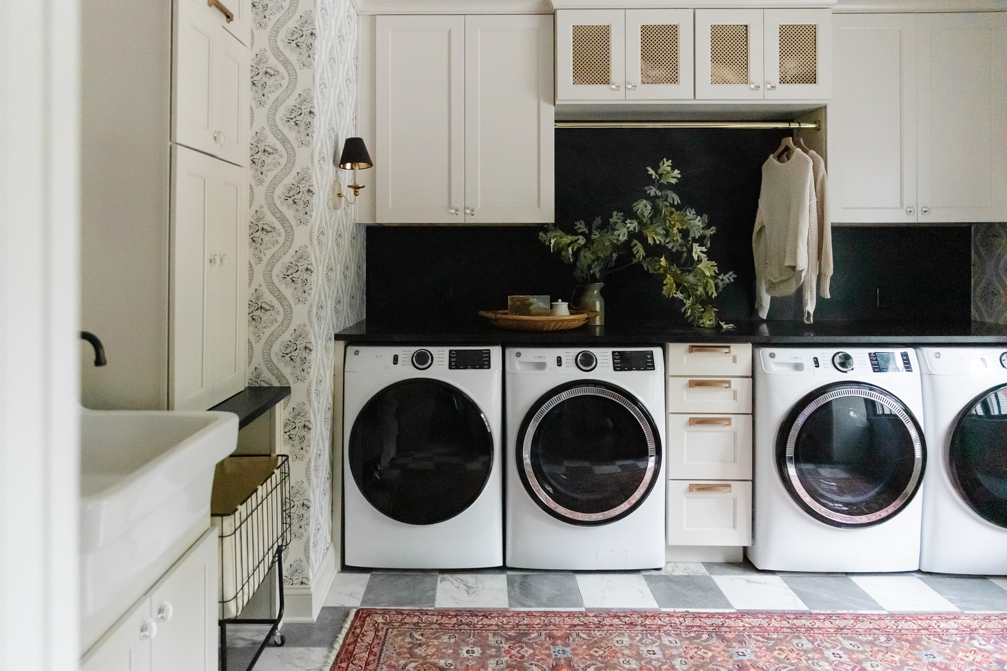 Chris Loves Julia | Laundry room with double washers and dryers, marble floors and vintage rug