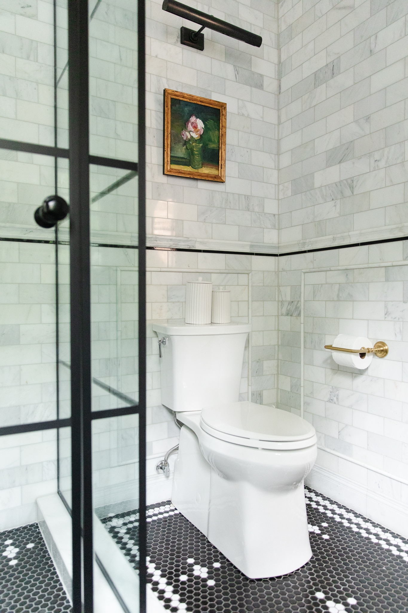 Chris Loves Julia | Greta's bathroom with marble tile walls and flower art