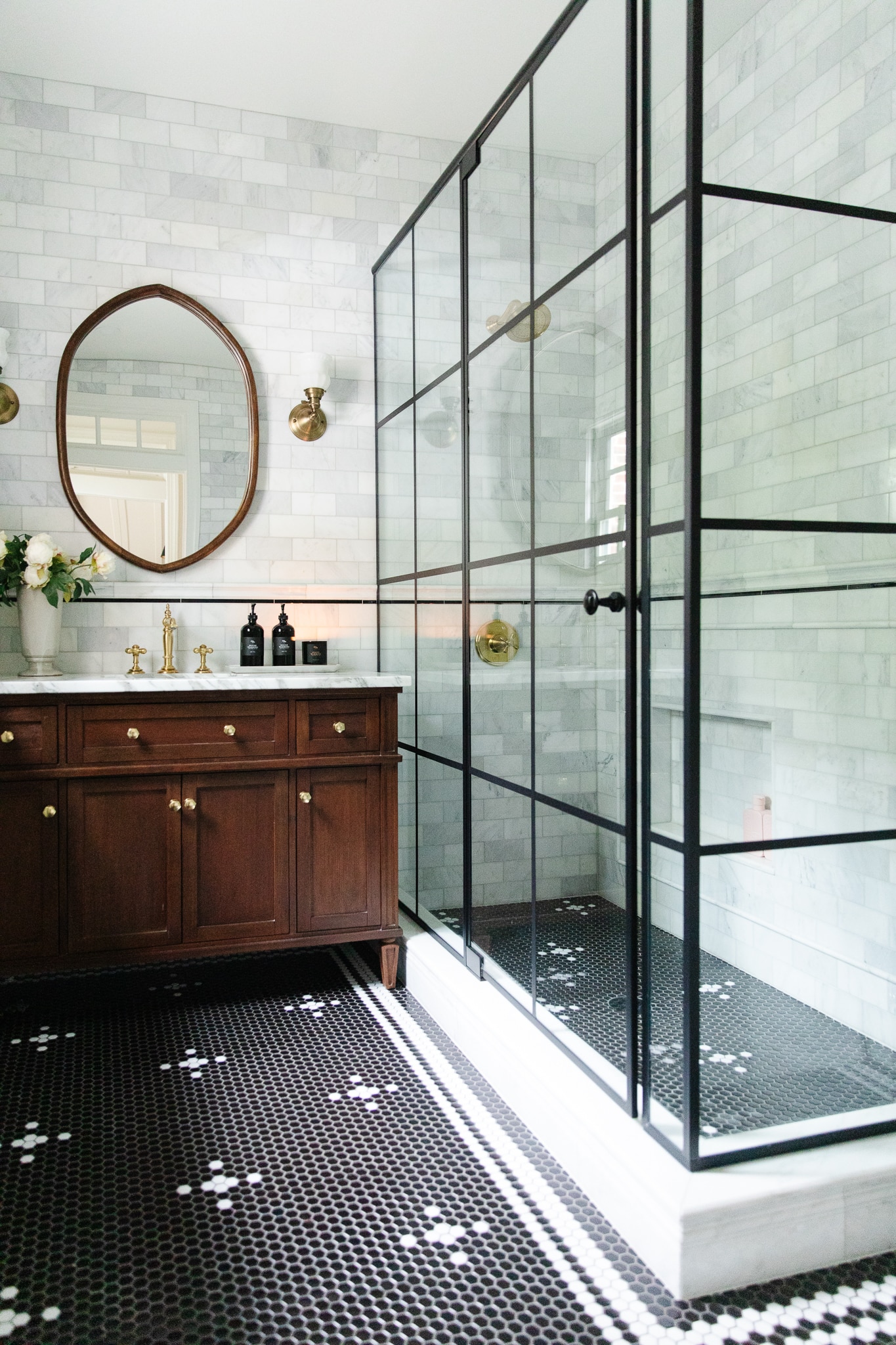Chris Loves Julia | Greta's bathroom with beautiful wood vanity and black grid glass shower