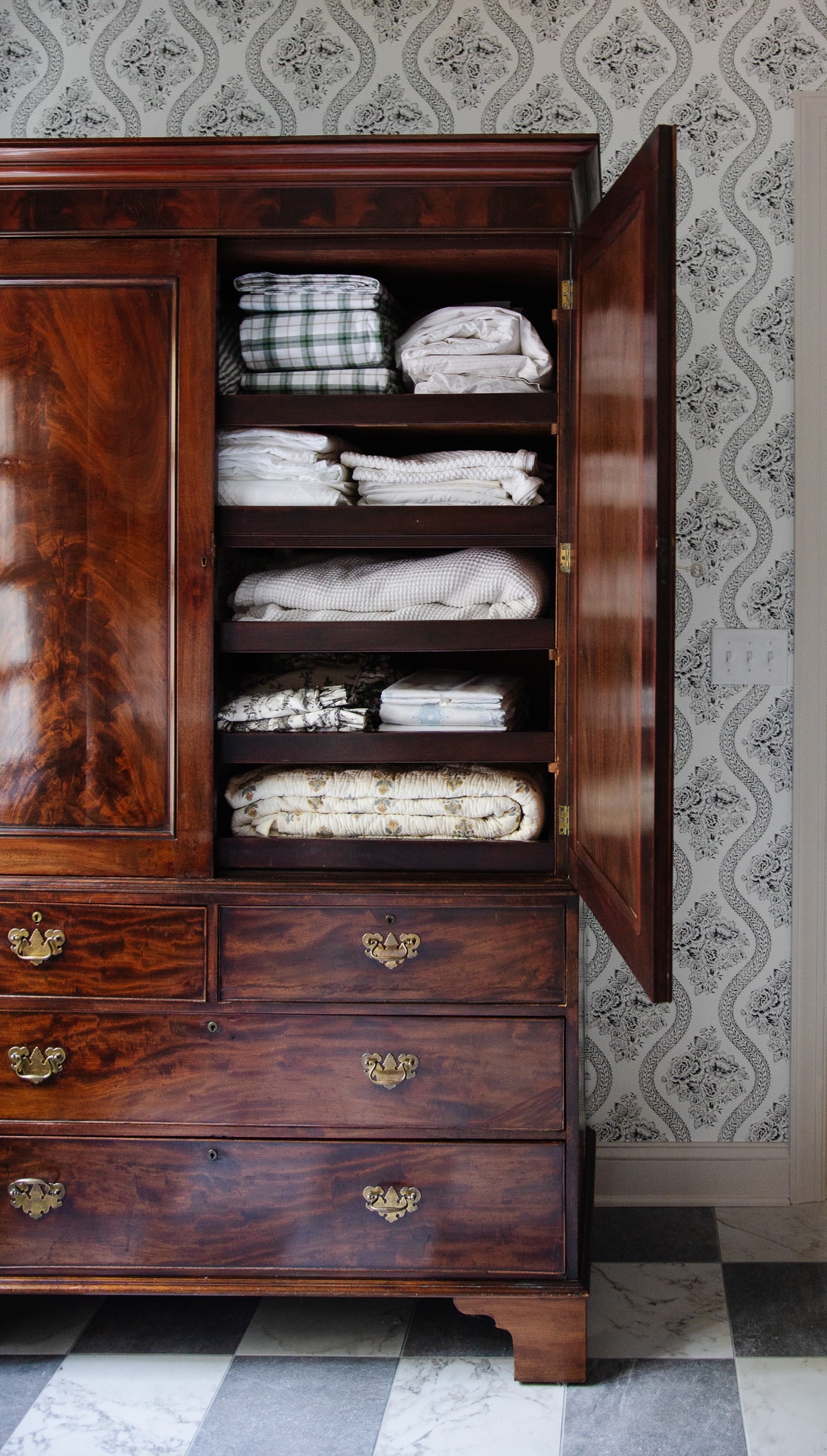 Chris Loves Julia | Antique wooden armoire open to show folded linens 