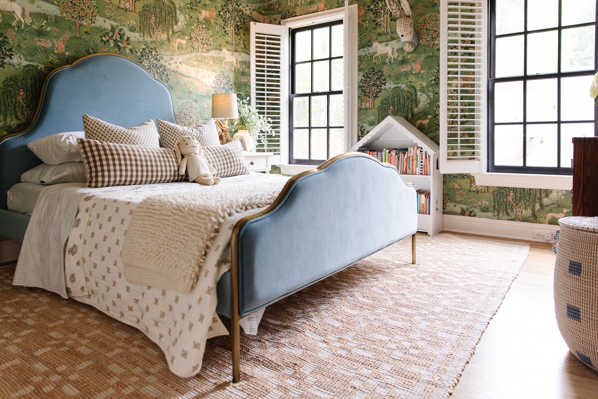 Chris Loves Julia | Polly's bedroom with blue upholstered bed and whimsical green wallpaper