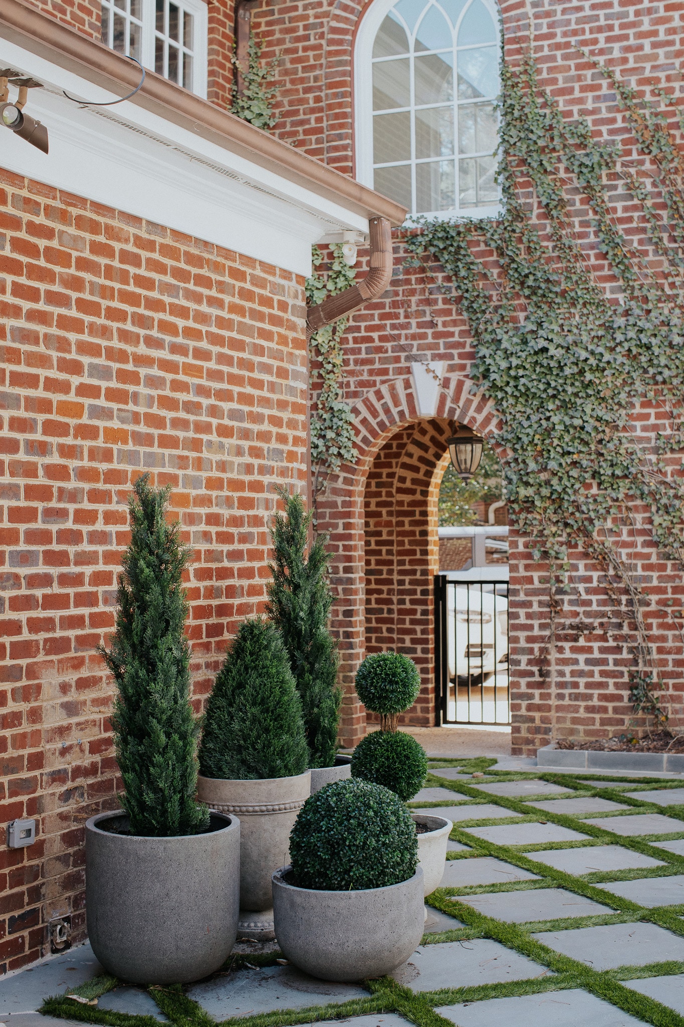 Chris Loves Julia | Outdoor planters with faux boxwood in front of brick house