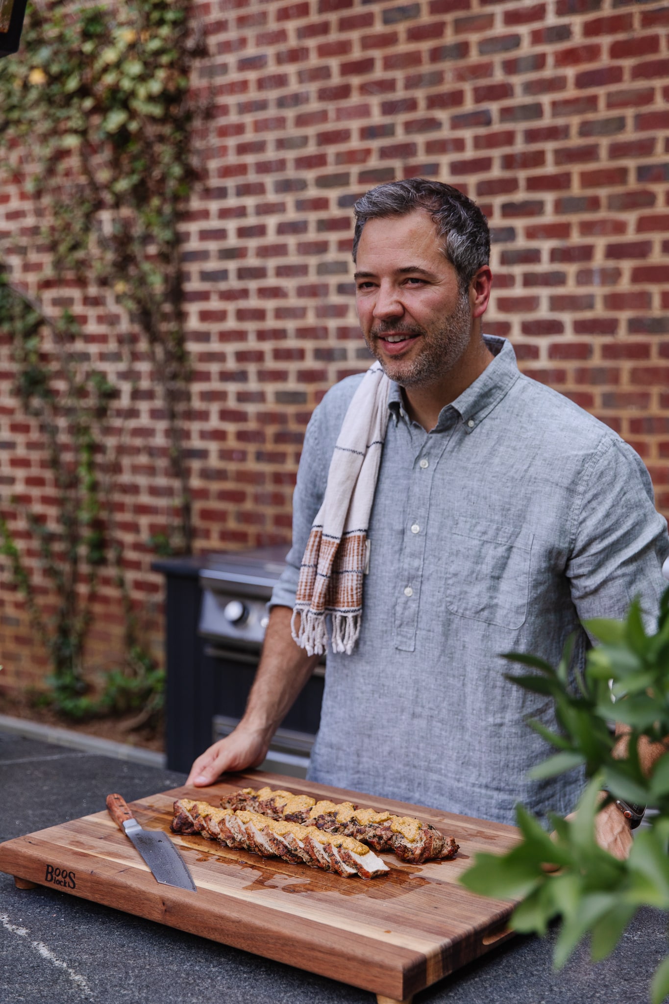 Chris Loves Julia | Chris in front of a wood cutting board featuring Grilled Pork Tenderloin with Macadamia Nut Pesto