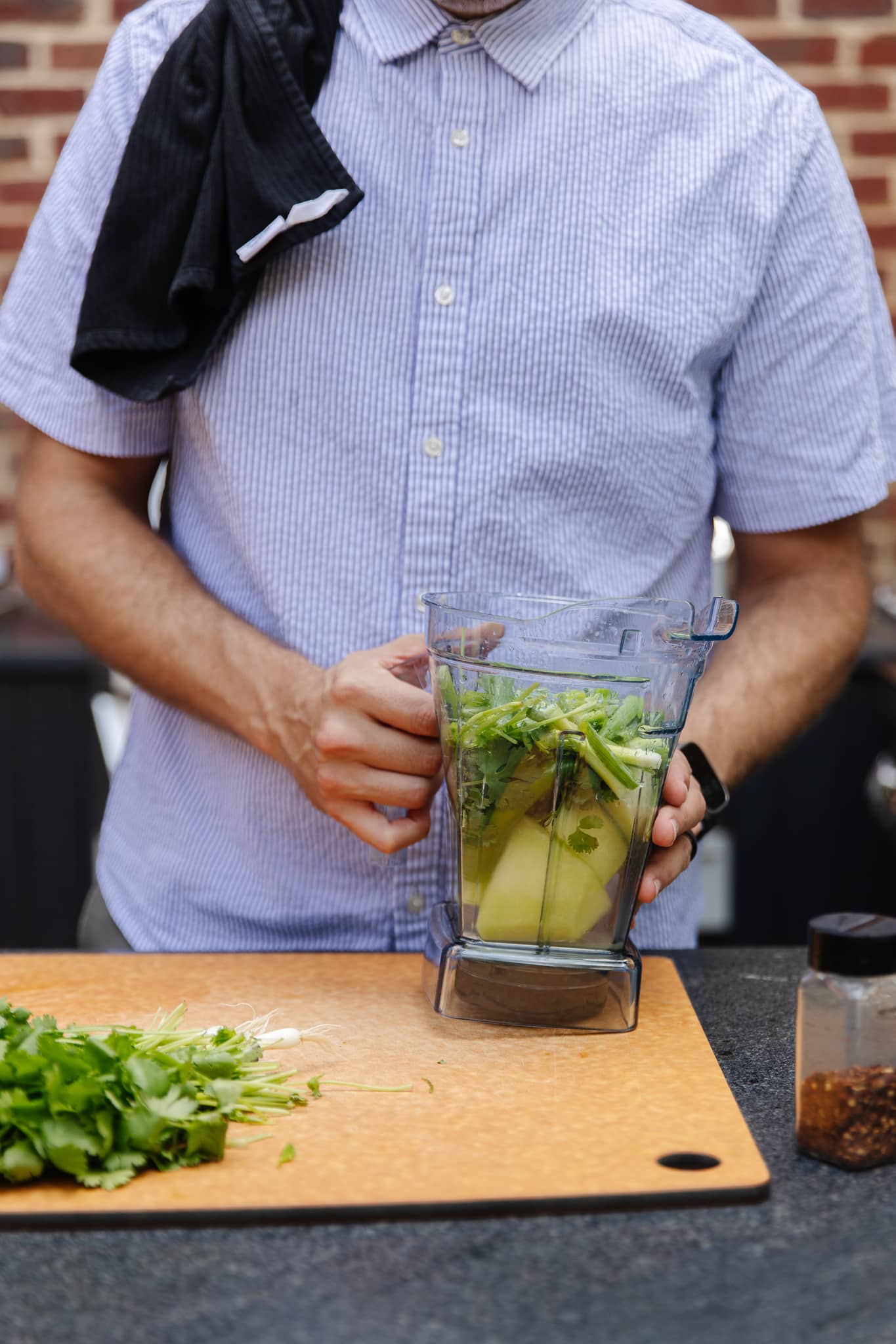 Chris holding a Vitamix blender filled with herbs, limes, and honeydew melon