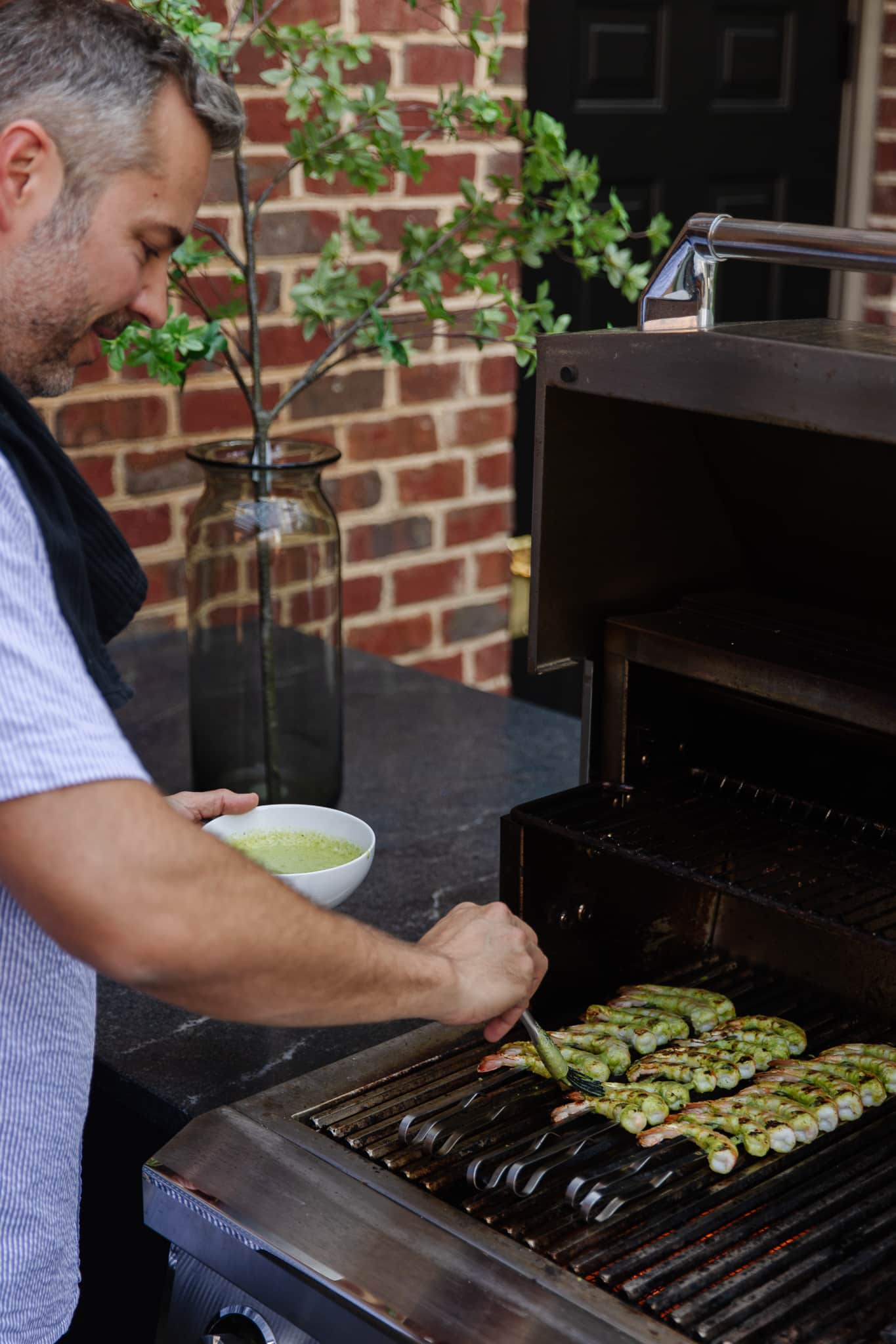 Chris brushing a citrus-spicy green marinade onto the skewers of shrimp on the grill